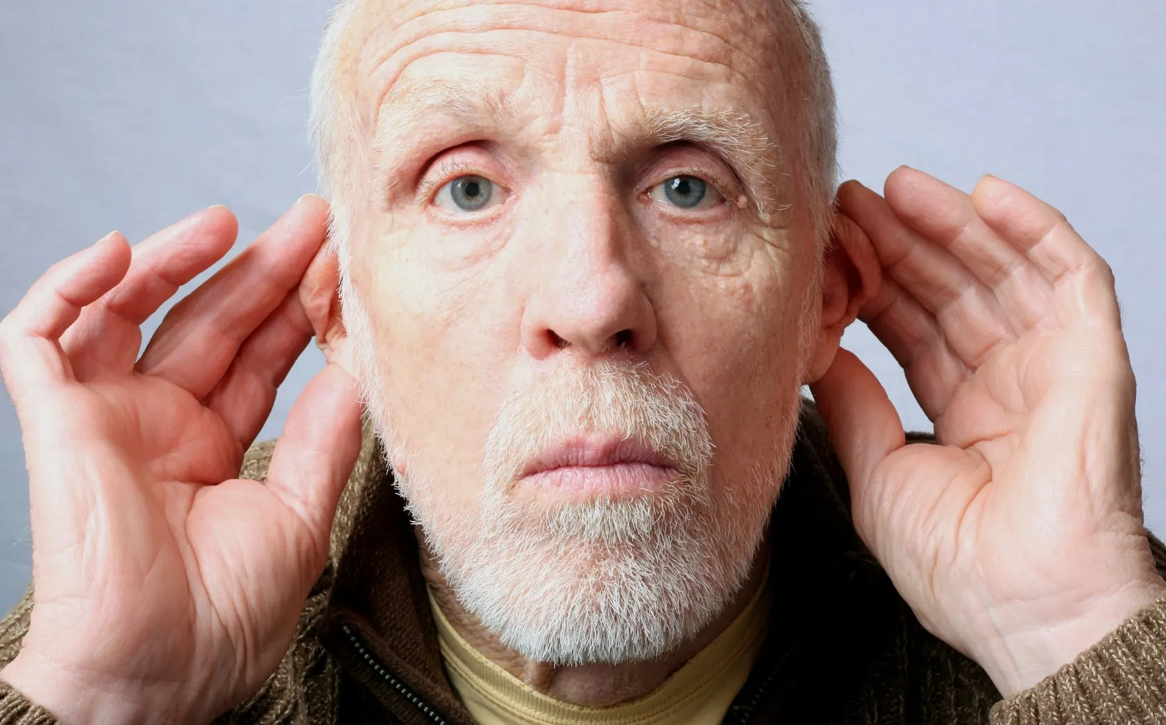 Homme âgé les mains derrière les oreilles pour mieux entendre
